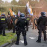 Dutch police in riot gear stand next to demonstrators including some with the Prince's Flag during a far-right rally named 'We Are The People' at the Malieveld in The Hague on September 19, 2026. (illistrative)