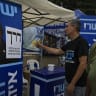 People and political party activists gather near election campaign posters outside a polling station in the southern Israeli city of Ashkelon during Israel’s general elections, October 27, 2026.