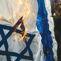 Demonstrators burn an Israeli flag in front of the Israeli Embassy in Bangkok
