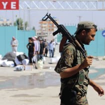 A KURDISH People’s Protection Units (YPG) fighter walks near residents who had fled Tel Abyad, as they reenter Syria from Turkey 