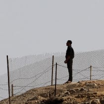  An Egyptian soldier stands near the Egyptian national flag and the Israeli flag at the Taba crossing between Egypt and Israel, about 430 km (256 miles) northeast of Cairo, October 26, 2011