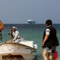  Armed men stand on the beach as the Galaxy Leader commercial ship, seized by Yemen's Houthis last month, is anchored off the coast of al-Salif, Yemen, December 5, 2023.