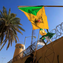  Un miembro de Hashd al-Shaabi (fuerzas paramilitares) sostiene una bandera del grupo miliciano Kataib Hezbollah durante una protesta para condenar los ataques aéreos en sus bases, fuera de la puerta principal de la Embajada de Estados Unidos en Bagdad, Irak, el 31 de diciembre de 2019.
