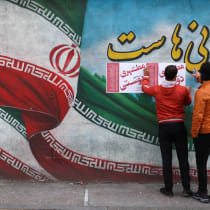  Iranian men put campaign posters on a wall during the last day of election campaigning in Tehran, Iran, February 28, 2024. 