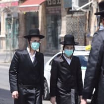  Hombres ultraortodoxos con máscaras caminan por el barrio de Mea Shearim, Jerusalén, 12 de abril de 2020.