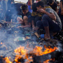  Palestinos buscan comida entre los escombros quemados tras un ataque israelí en una zona designada para desplazados, en Rafah, en el sur de la Franja de Gaza, 27 de mayo de 2024.