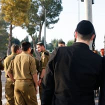  Hombres haredíes vestidos con atuendos ultraortodoxos tradicionales detrás de un grupo de soldados religiosos de las FDI.