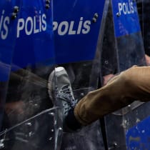  Un hombre empuja con la pierna el escudo de un policía antidisturbios durante los enfrentamientos, mientras los manifestantes intentan desafiar una prohibición y marchar en la plaza Taksim para celebrar el Primero de Mayo en Estambul, Turquía, 1 de mayo de 2024.