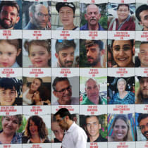 Un grupo de personas camina junto a un muro que muestra carteles de rehenes, en Tel Aviv, Israel, 18 de agosto de 2024 