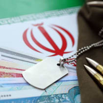  Se ven balas y billetes de rial iraní colocados sobre la bandera de la República Islámica de Irán (ilustrativo)