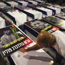  A MAN lights a candle next to a picture of the late Hersh Goldberg-Polin adorned with flowers, in Tel Aviv last week.