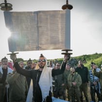 IDF reserve soldiers and Orthodox Jews reading from a Torah scroll at dawn.