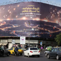  Commuters drive past an anti-Israel billboard covering the facade of a building in Tehran on October 26, 2024. 