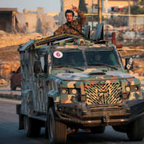 A rebel led by the Islamist group Hayat Tahrir al-Sham stands in the back of a vehicle in al-Rashideen, Aleppo province, Syria November 29, 2024. 