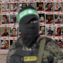  A Hamas terrorists in front of hostage posters. (Illustrative)