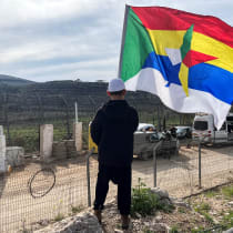A Druze boy holds a flag as he looks at the ceasefire line between Golan Heights and Syria, on the day of first visit by Druze delegation from Syria just after 1973 war in Israel, March 14, 2025. 