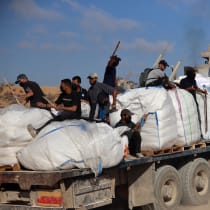 Hamas terrorists carrying clubs and firearms secure humanitarian aid trucks in the northern Gaza area of Jabaliya on June 25, 2025. 