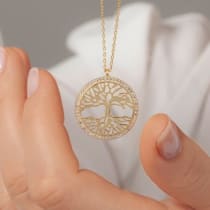 Primer plano del retrato de una mujer elegante que lleva un elegante collar de oro con un colgante redondo. Joyería minimalista, belleza femenina y detalle de moda.