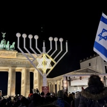 The Israeli flag waves as lights are lit on the Hanukkah candelabrum during a ceremony of the Jewish Hanukkah festival of lights at Brandenburg Gate, in Berlin, Germany December 14, 2025.
