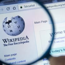 Página de inicio de Wikipedia en la pantalla del ordenador bajo una lupa. Wikipedia es una enciclopedia gratuita en Internet.