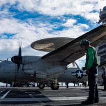 Marineros de la Armada de los Estados Unidos observan cómo un avión E-2D Hawkeye se aproxima a una catapulta para despegar desde la cubierta de vuelo del portaaviones USS Gerald R. Ford, mientras opera en apoyo de la operación Epic Fury contra Irán desde una ubicación no revelada el 1 de marzo 