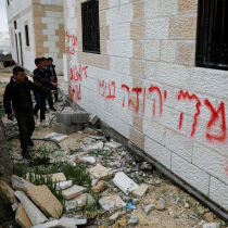 Boys stand near graffiti, which Palestinians say was written by Israeli settlers, near Hebron.