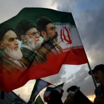 Un hombre sostiene una bandera con la imagen del difunto líder de la Revolución Islámica, el ayatolá Ruhollah Jomeini; del difunto líder supremo de Irán, el ayatolá Alí Jamenei; y del nuevo líder supremo de Irán, Mojtaba Jamenei, durante una manifestación celebrada en Teherán, Irán
