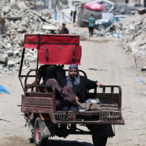 Unos palestinos pasan junto a los escombros de unos edificios residenciales destruidos durante la ofensiva israelí, en la ciudad de Gaza, el 23 de junio de 2026. 
