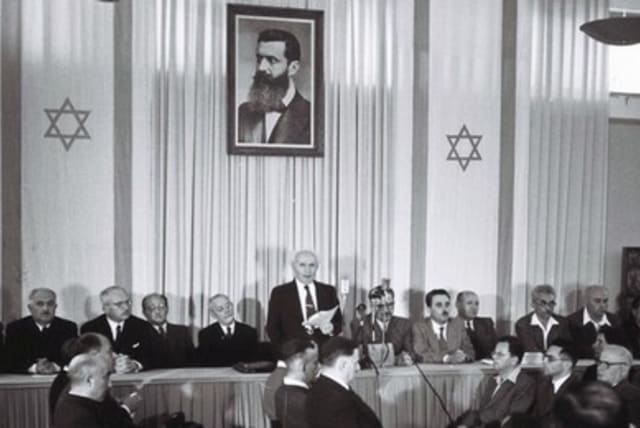 ISRAEL’S FIRST prime minister David Ben-Gurion (center) stands under a portrait depicting Theodore Herzl, the father of modern Zionism, as he reads Israel’s Declaration of Independence in Tel Aviv May 14, 1948.  (photo credit: REUTERS)