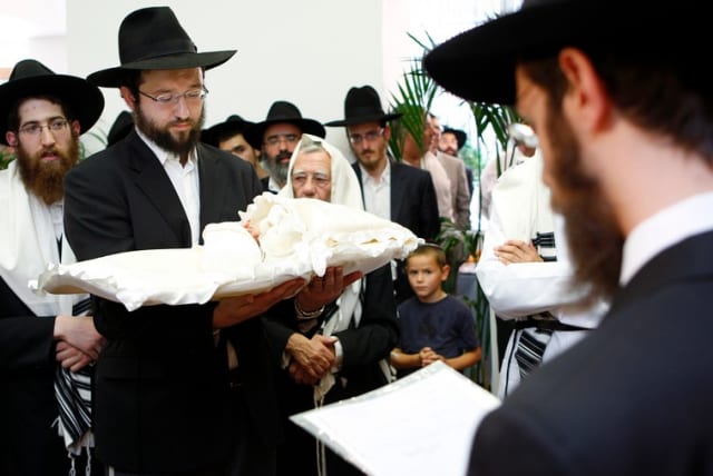A rabbi holds an eight-day-old baby during a circumcision ceremony in Brussels, August 20, 2009. (photo credit: REUTERS)