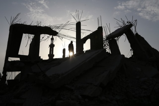 A Palestinian man walks atop the remains of a house that witnesses said was destroyed by Israeli shelling during a 50-day war last summer, in the southern Gaza Strip, March 10 (photo credit: REUTERS)