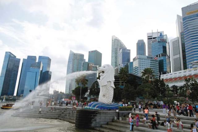TOURISTS TAKE pictures next to the Merlion statue in the central business district of Singapore, last month. (photo credit: REUTERS)