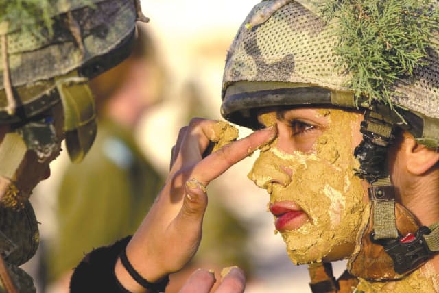 A SOLDIER paints the face of a comrade. (photo credit: REUTERS)