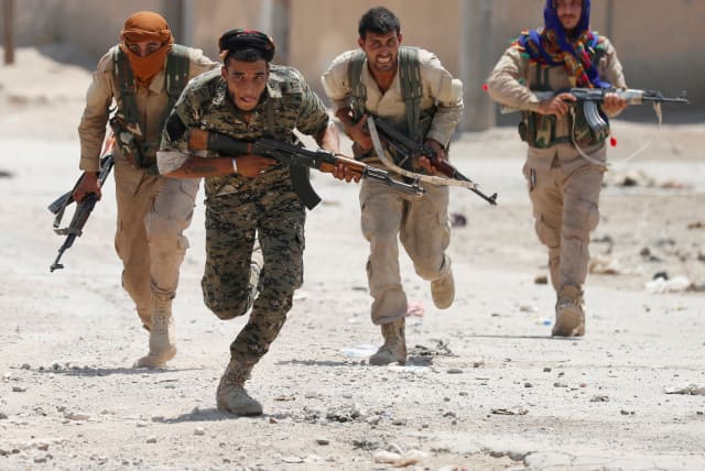 Kurdish fighters from the People's Protection Units (YPG) run across a street in Raqqa, Syria  (photo credit: REUTERS/GORAN TOMASEVIC/FILE PHOTO)