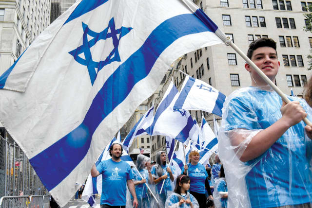 American Jews marching in New York with Israeli flags. How can we bridge the divide between Israel and the Diaspora? (photo credit: REUTERS)