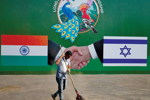 A municipal worker cleans the street in front of a bilboard displaying Indian and Israeli flags for PM Netanyahu's visit, Ahmedabad, India, January 2018 (photo credit: REUTERS/AMIT DAVE)