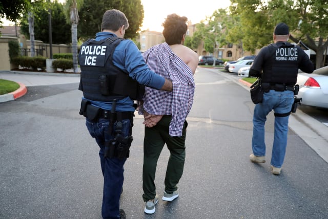 Immigration and Customs Enforcement agents escort an immigrant (photo credit: LUCY NICHOLSON / REUTERS)