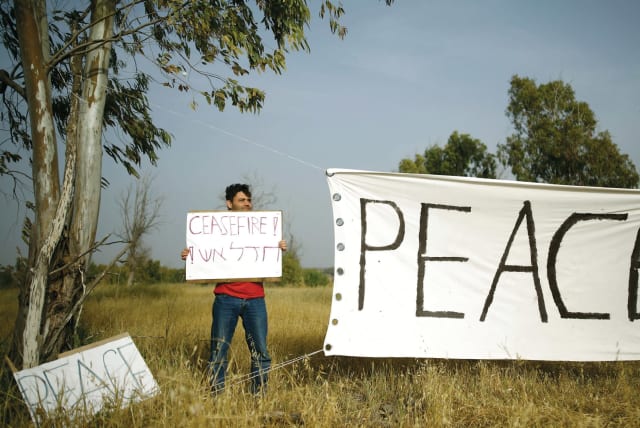 A PEACE activist holds up a sign near Gaza. (photo credit: REUTERS)