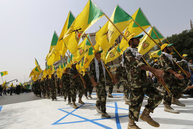 Iraqi Shi'ite Muslim men from the Iranian-backed group Kataib Hezbollah wave the party's flags as they walk along a street painted in the colours of the Israeli flag during a parade marking the annual Quds Day, or Jerusalem Day, on the last Friday of the Muslim holy month of Ramadan, in Baghdad (photo credit: THAIER AL-SUDANI/REUTERS)