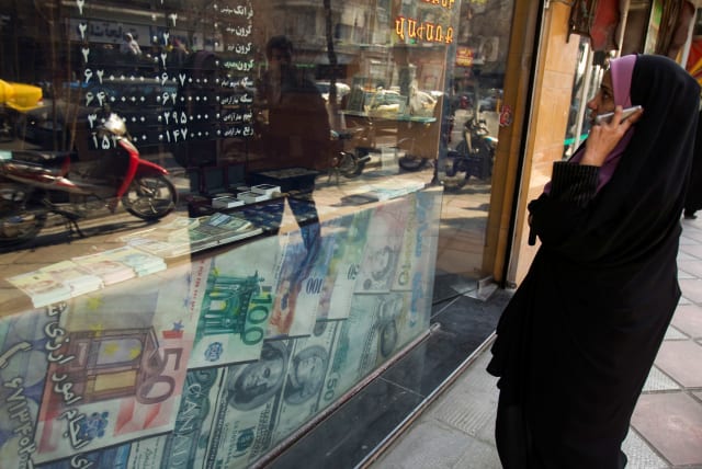 A woman looks at exchange rates by the window of a currency exchange shop in Tehran's business district, Iran (photo credit: RAHEB HOMAVANDI/REUTERS)