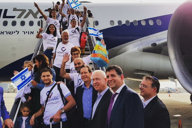 Jewish Agency for Israel chairman Isaac Herzog and Keren Hayesod Chairman Sam Grundwerg pose with French immigrants as they disembark from their aliya flight. (photo credit: AVI HAYUN/KEREN HAYESOD)