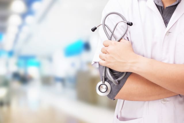 Doctor with a stethoscope in the hands and hospital background (illustrative) (photo credit: INGIMAGE)