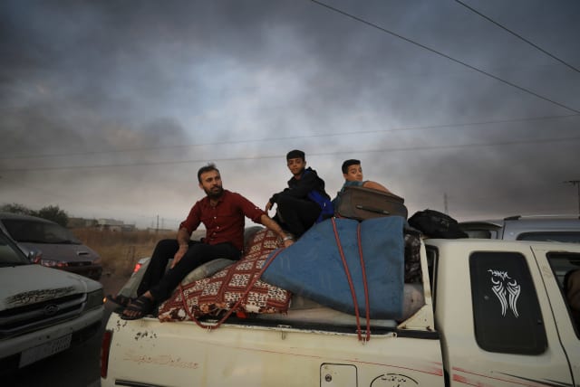People sit on belongings at a back of a truck as they flee Ras al Ain town, Syria (photo credit: REUTERS/RODI SAID)