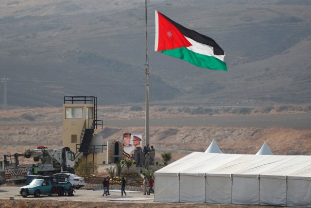 A Jordanian national flag is lifted near a tent at the "Island of Peace" in an area known as Naharayim in Hebrew and Baquora in Arabic, on the Jordanian side of the border with Israel, as seen from the Israeli side November 10, 2019 (photo credit: RONEN ZVULUN/REUTERS)