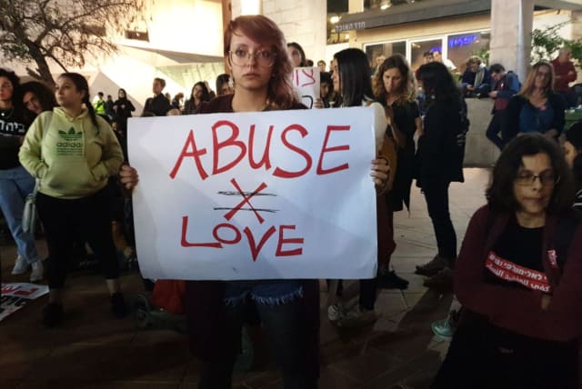 A protester holding an "Abuse isn't Love" sign at a protest against violence against women in Tel Aviv (photo credit: TAMAR BEERI)