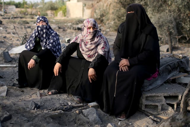 Palestinian women sit at the debris of a house destroyed in an air strike in the southern Gaza Strip November 13, 2019 (photo credit: REUTERS/IBRAHEEM ABU MUSTAFA)