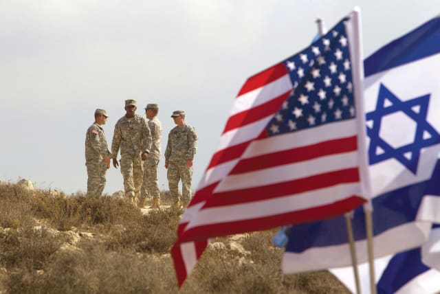 US SOLDIERS stand in the background next to Israeli and American flags during an exercise in Israel. (photo credit: REUTERS)