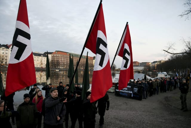 Finnish neo-nazis start their Independence Day march with swastika flags in Helsinki, Finland December 6, 2018. (photo credit: MARTTI KAINULAINEN/LEHTIKUVA/VIA REUTERS)