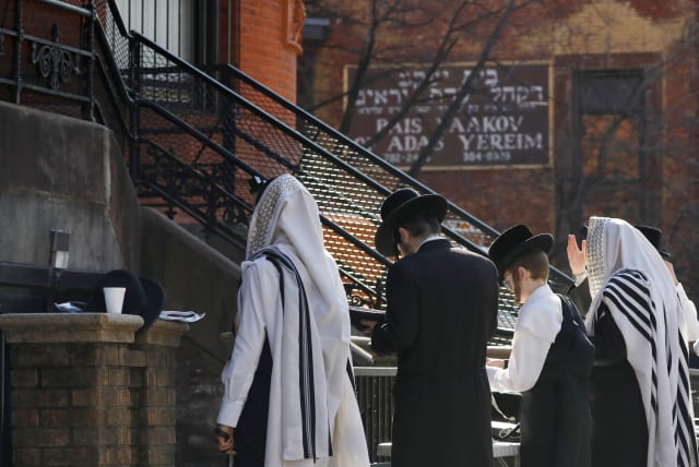 Hasidic Jewish men gather for a morning prayer outside of a synagogue, closed due to coronavirus disease (COVID-19), in South Williamsburg, Brooklyn, New York City, New York (photo credit: REUTERS)
