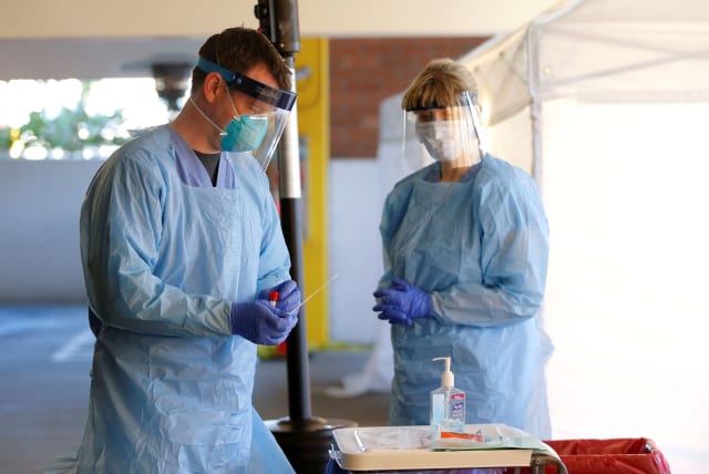 FILE PHOTO: Nurse Jeff Gates processes a patient sample at a drive-through testing clinic for coronavirus, flu and RSV, currently by appointment for employees at UW Medical Center Northwest in Seattle, Washington, U.S. March 9, 2020 (photo credit: REUTERS/LINDSEY WASSON)